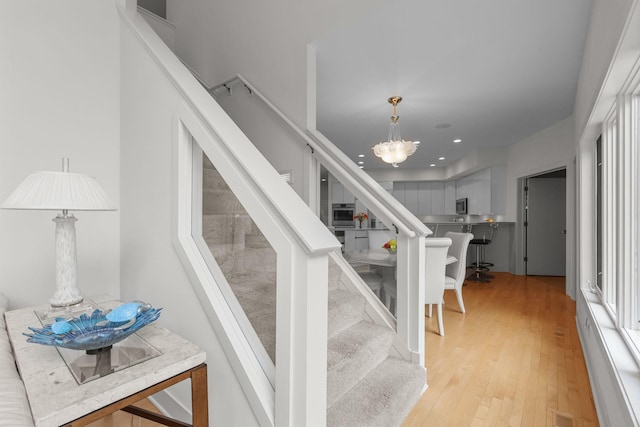 staircase featuring hardwood / wood-style floors and an inviting chandelier