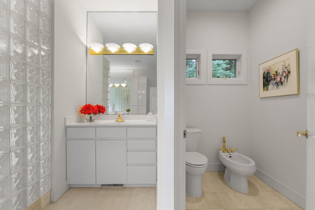 bathroom with toilet, vanity, tile patterned flooring, and a bidet