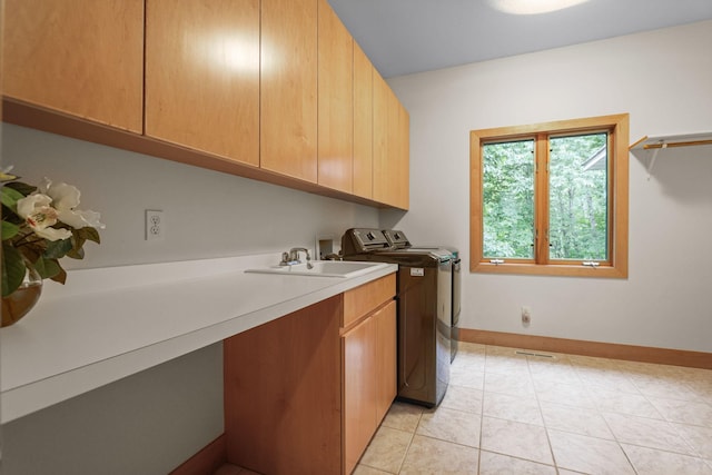 laundry area featuring washing machine and dryer, cabinets, light tile patterned flooring, and sink