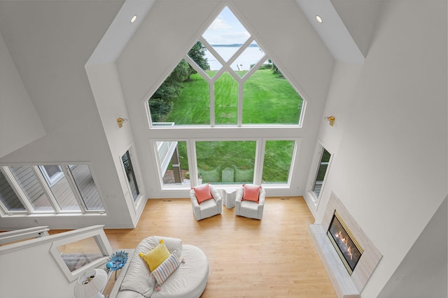 living room featuring light wood-type flooring, a tiled fireplace, and a towering ceiling