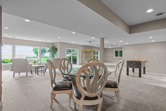 dining room featuring ceiling fan, light colored carpet, and a textured ceiling