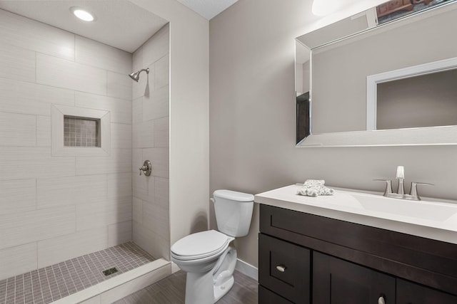 bathroom featuring toilet, vanity, and a tile shower