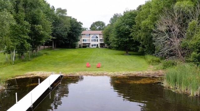 view of dock with a lawn and a water view