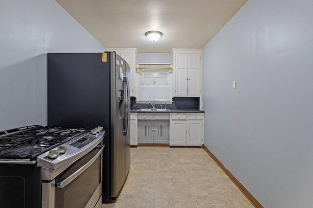 kitchen featuring gas range, white cabinetry, light tile patterned floors, and sink