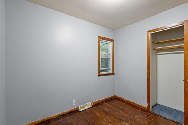 unfurnished bedroom with dark hardwood / wood-style flooring and a closet