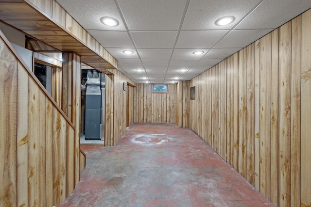 basement featuring wooden walls and a drop ceiling