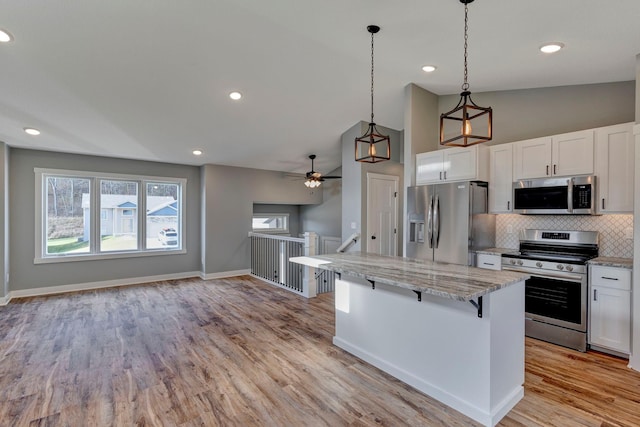 kitchen with stainless steel appliances, light hardwood / wood-style floors, a kitchen breakfast bar, lofted ceiling, and white cabinets