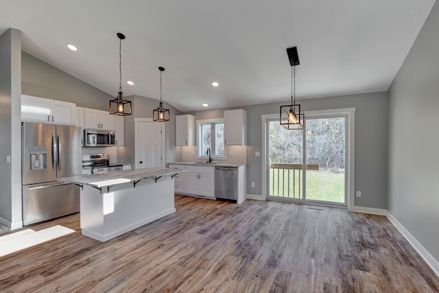 kitchen with white cabinetry, appliances with stainless steel finishes, lofted ceiling, a kitchen island, and light wood-type flooring