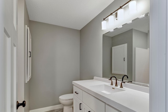 bathroom with toilet, vanity, and a textured ceiling