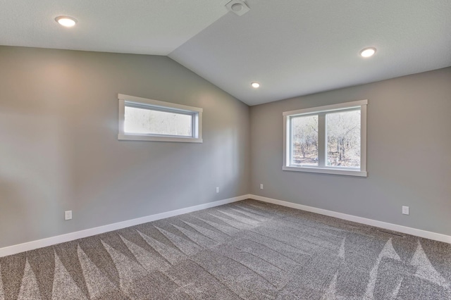 carpeted spare room with vaulted ceiling