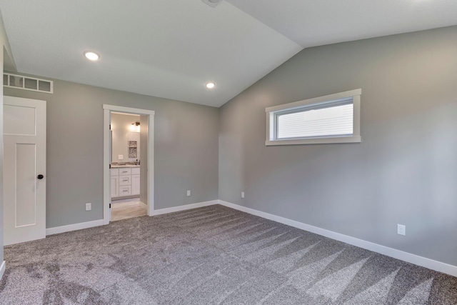 unfurnished bedroom featuring lofted ceiling, carpet flooring, and ensuite bathroom