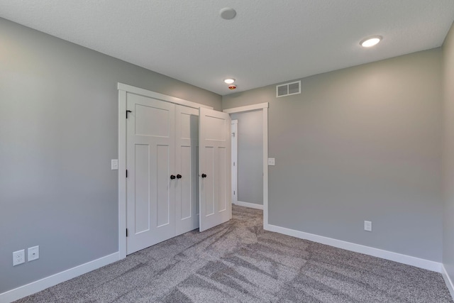 unfurnished bedroom featuring carpet, a textured ceiling, and a closet