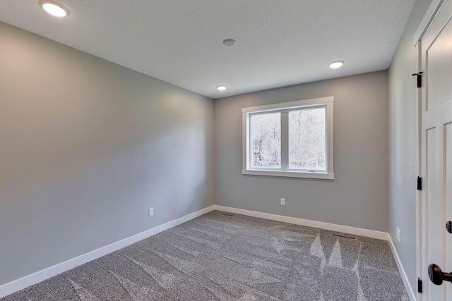 carpeted empty room with a textured ceiling