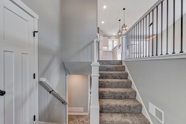 staircase featuring an inviting chandelier and carpet flooring