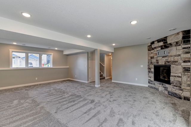 basement featuring a stone fireplace, carpet, and a textured ceiling