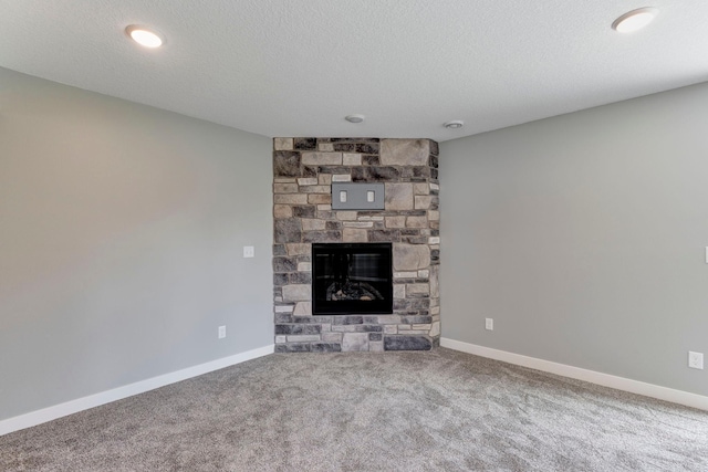 unfurnished living room with a stone fireplace, a textured ceiling, and carpet floors