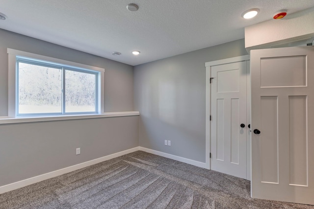 carpeted empty room with a textured ceiling