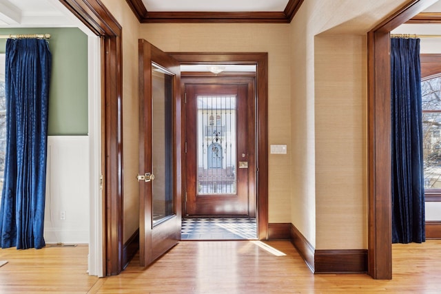 entryway with ornamental molding, light wood-type flooring, and baseboards