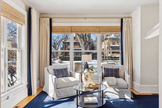 living area featuring a wealth of natural light, baseboards, and wood finished floors