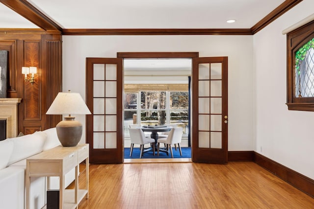 doorway with light wood finished floors, baseboards, a premium fireplace, crown molding, and french doors