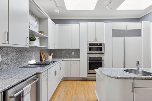 kitchen with stainless steel appliances, a skylight, a sink, white cabinetry, and open shelves