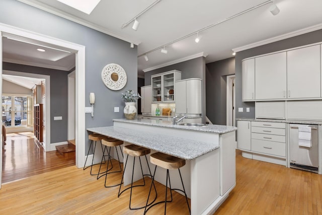 kitchen with glass insert cabinets, ornamental molding, white cabinetry, a peninsula, and a kitchen breakfast bar