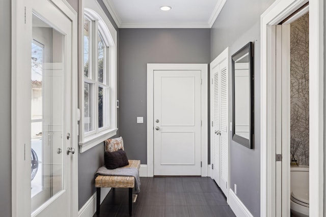 entryway with baseboards and crown molding