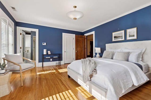 bedroom with baseboards, visible vents, ornamental molding, wood finished floors, and a closet