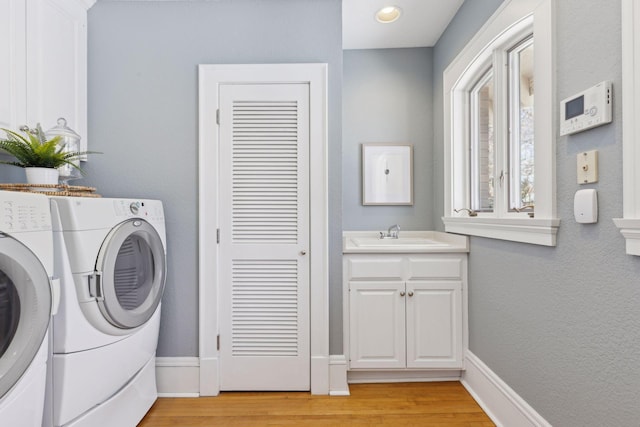 laundry room featuring light wood-style flooring, baseboards, a sink, and washing machine and clothes dryer