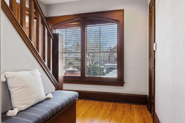 sitting room featuring a textured wall, stairway, wood finished floors, and baseboards