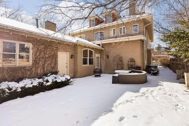 snow covered rear of property featuring an outdoor fire pit and fence