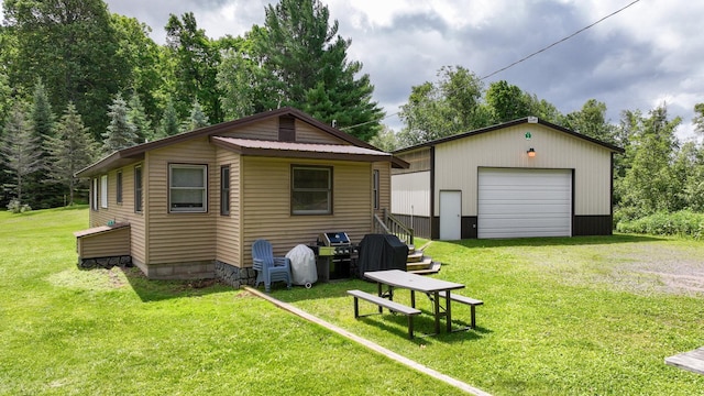 back of house featuring an outbuilding, a yard, and a garage