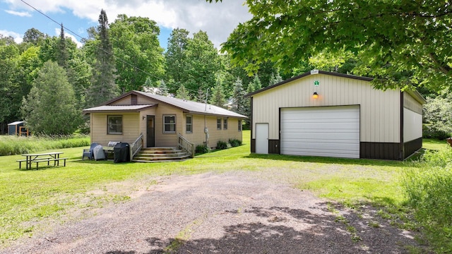 view of front facade featuring a garage, an outbuilding, and a front yard