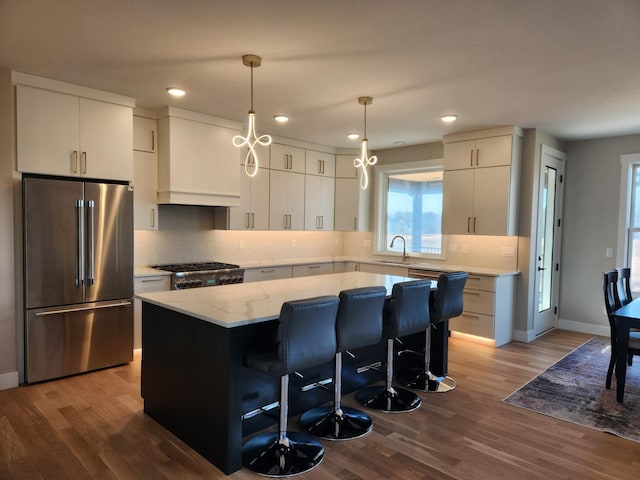 kitchen with a kitchen island, sink, white cabinets, range, and high end fridge