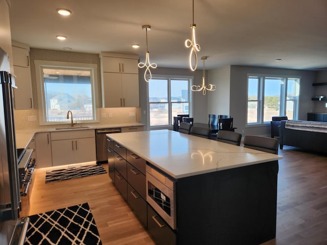 kitchen with white cabinetry, hanging light fixtures, appliances with stainless steel finishes, and a kitchen island