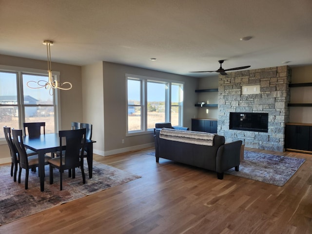 living room featuring hardwood / wood-style flooring, a fireplace, and ceiling fan with notable chandelier