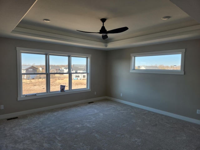 carpeted spare room with a tray ceiling and ceiling fan