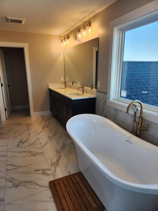 bathroom with vanity, a bath, and a textured ceiling