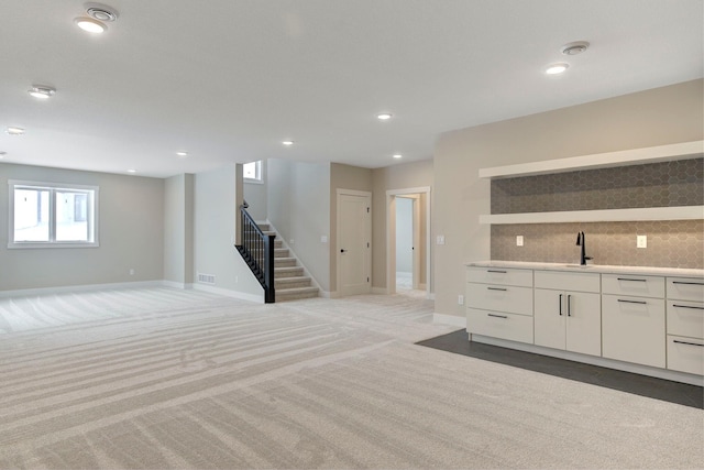 unfurnished living room with sink and light carpet