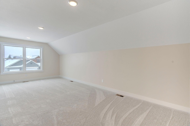 additional living space featuring vaulted ceiling and carpet flooring