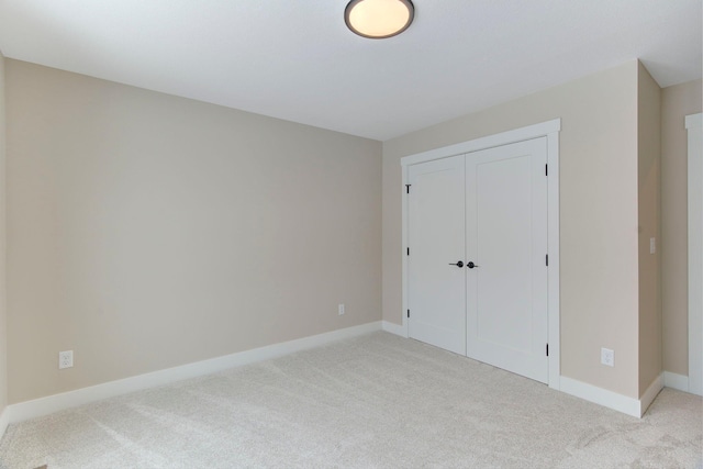 unfurnished bedroom with light carpet and a closet