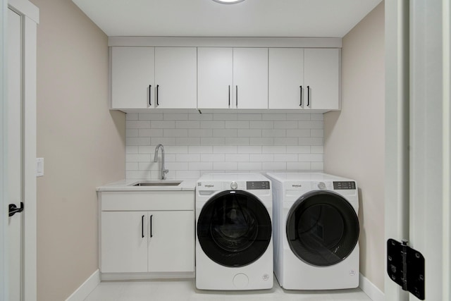 laundry room with sink, washer and clothes dryer, and cabinets