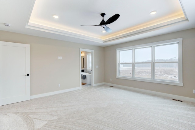 carpeted spare room with ceiling fan and a raised ceiling