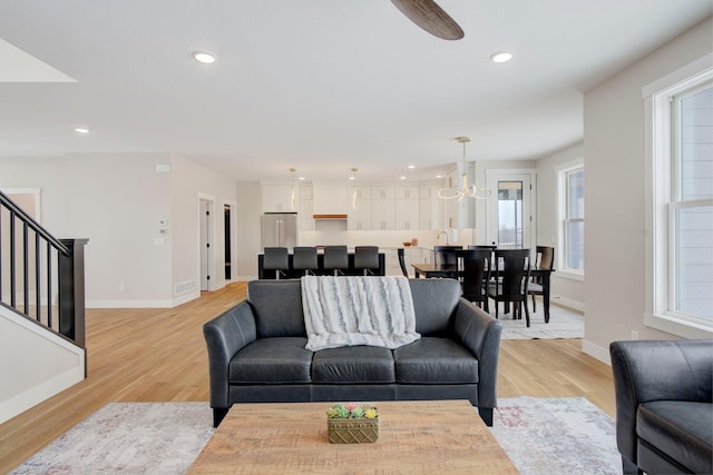 living room with a wealth of natural light, a chandelier, and light hardwood / wood-style flooring