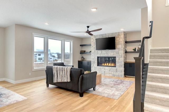 living room with a fireplace, light hardwood / wood-style floors, and ceiling fan