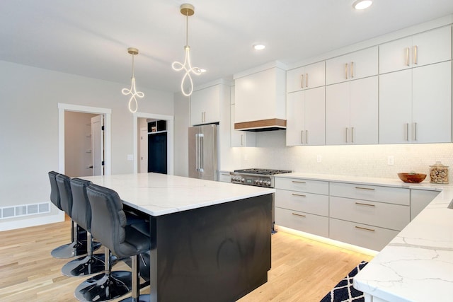 kitchen featuring hanging light fixtures, high end refrigerator, a center island, and white cabinets