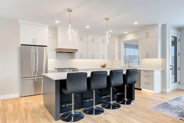 kitchen with a kitchen island, white cabinets, stainless steel fridge, hanging light fixtures, and light hardwood / wood-style flooring