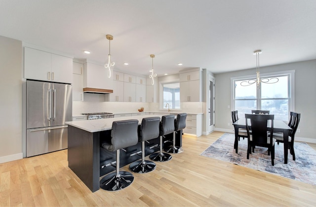 kitchen featuring white cabinetry, a center island, stainless steel fridge, and decorative light fixtures