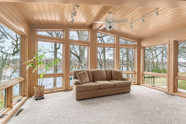 sunroom / solarium with a healthy amount of sunlight, vaulted ceiling with beams, and rail lighting