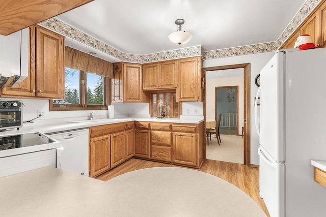 kitchen with sink, light wood-type flooring, hanging light fixtures, and white appliances